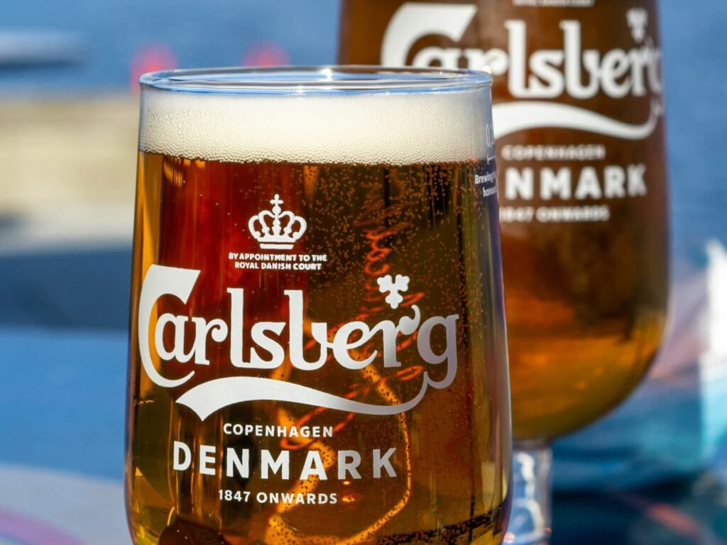 Carlsberg classic lager øl i et ølglas med en blå baggrund