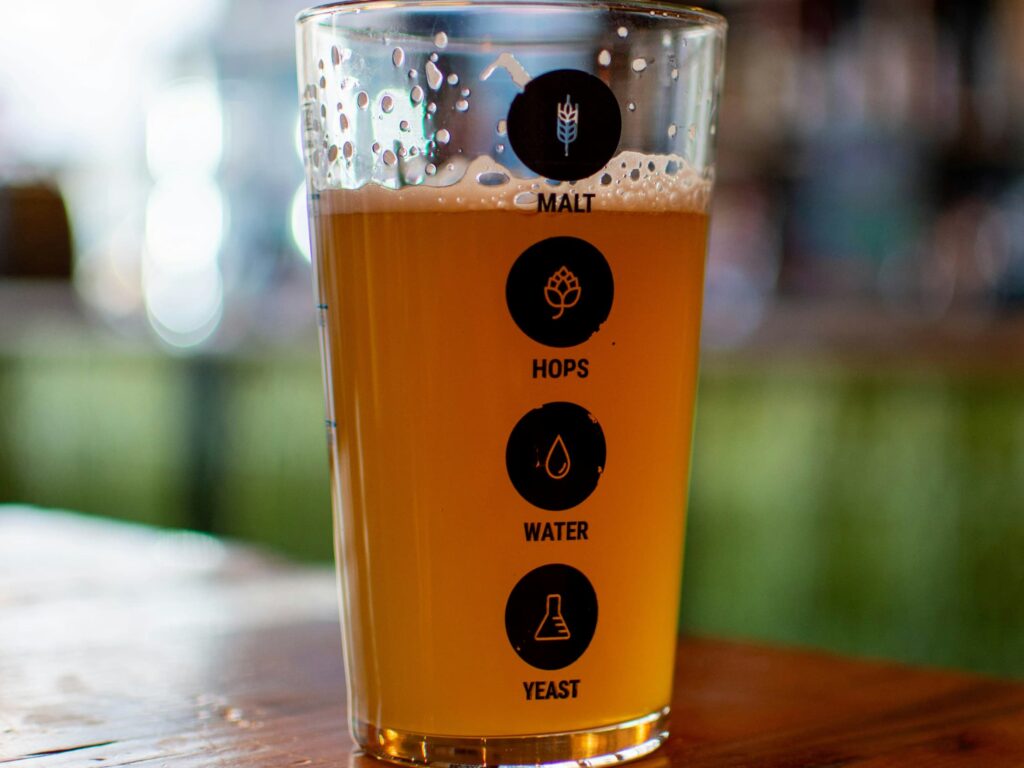 ipa øl et glas med 4 runde sorte ikoner på stående på træbord